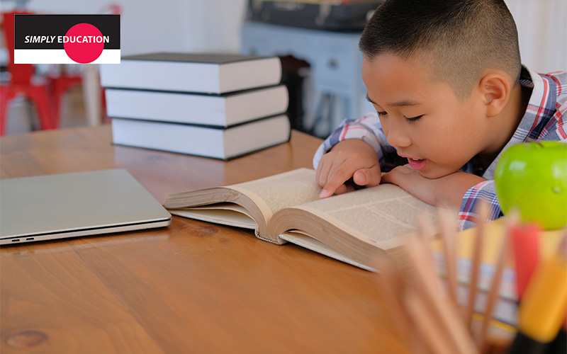 A boy reading a book at his study desk.