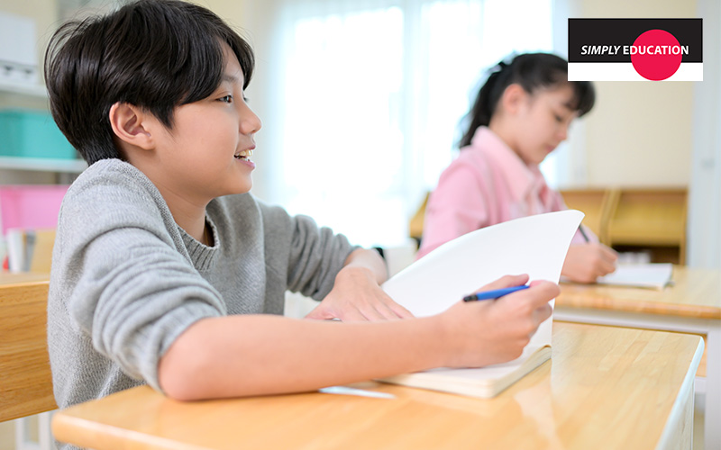 A male student attentively taking notes in class.