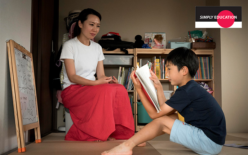 A parent listening to their child read a book.